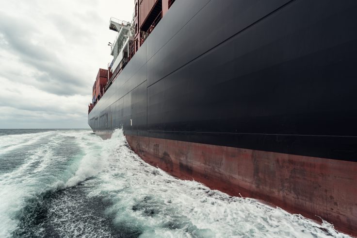 A 200m (600') long container ship navigates the North Atlantic under dramatic skies. Wide angle view taken at sea level.